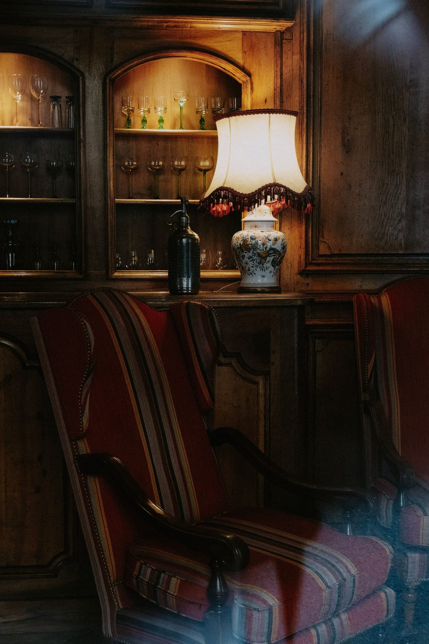 Warm wooden bar counter and classic furniture under soft golden light, a textural close detail of a cosy venue interior