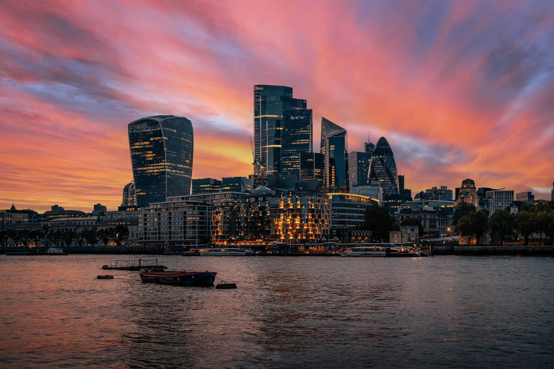 London at golden hour — the Thames and city skyline under a warm sunset sky, with calm open sky for text